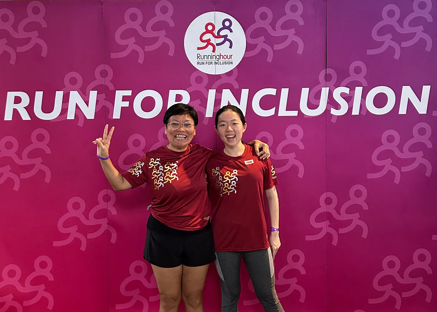 Two women standing in front of a purple backdrop with the words "Run for Inclusion"