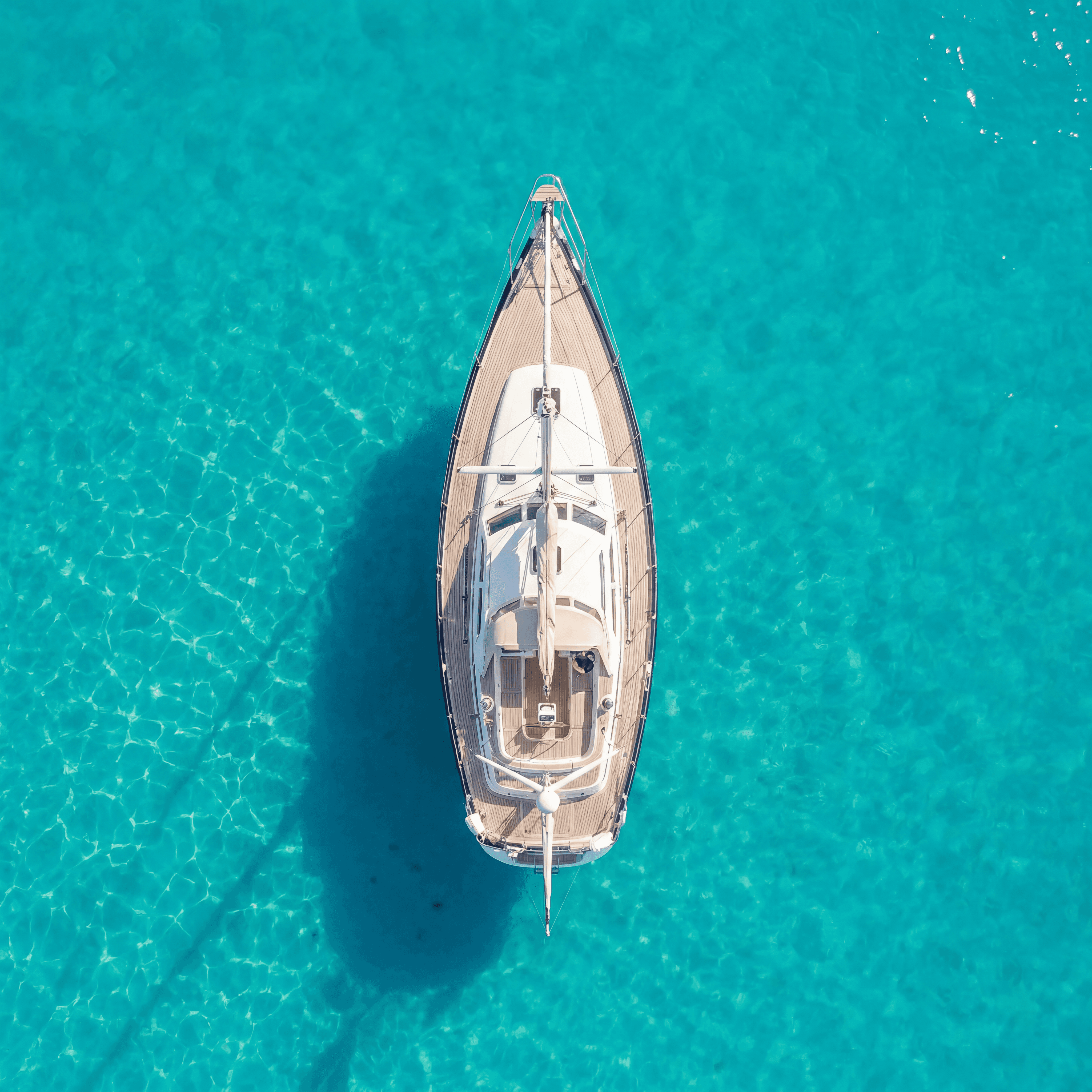 Overhead night aerial photograph of a Beneteau Clipper 361 sailing yacht with warm interior cabin lighting illuminating the teak deck, set against a dark black ocean background