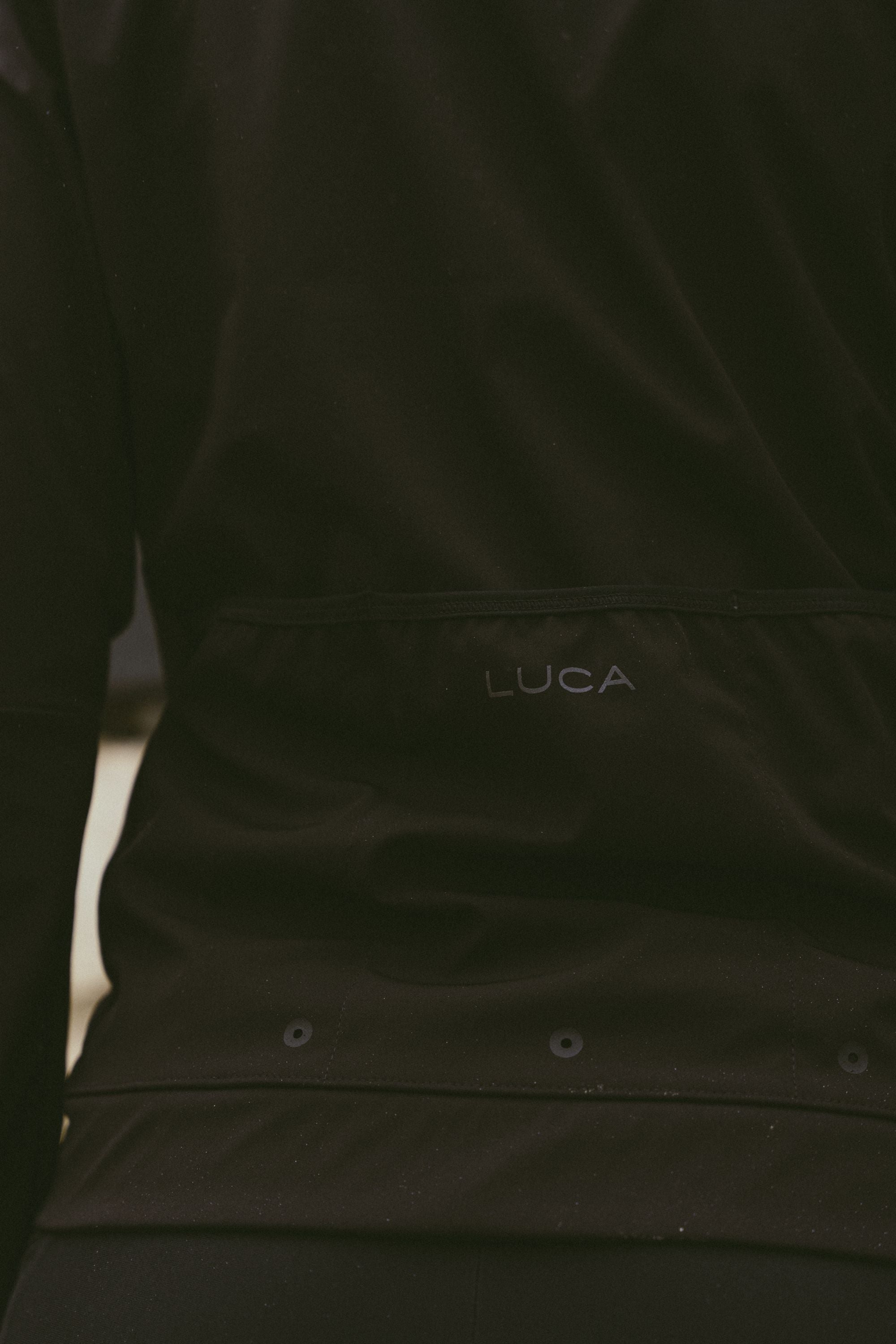Back-detail-of-the-Luca-Momentum-Jacket-in-black-featuring-the-discrete-logo-and-horizontal-rear-pocket-design