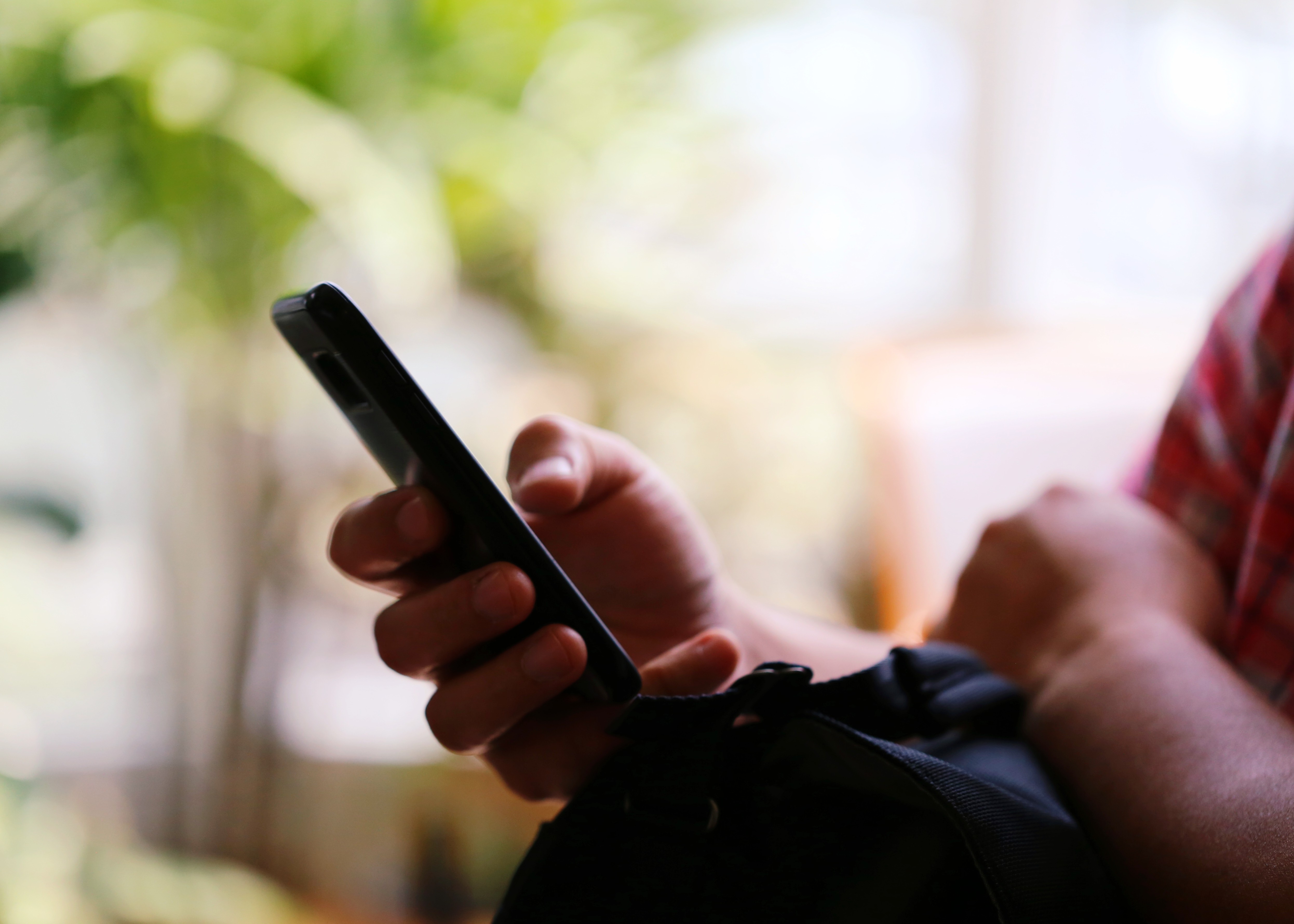 Close-up of a desk with a pair of tortoiseshell glasses, a lanyard with an ID badge, a pencil, and a notebook in soft natural light.