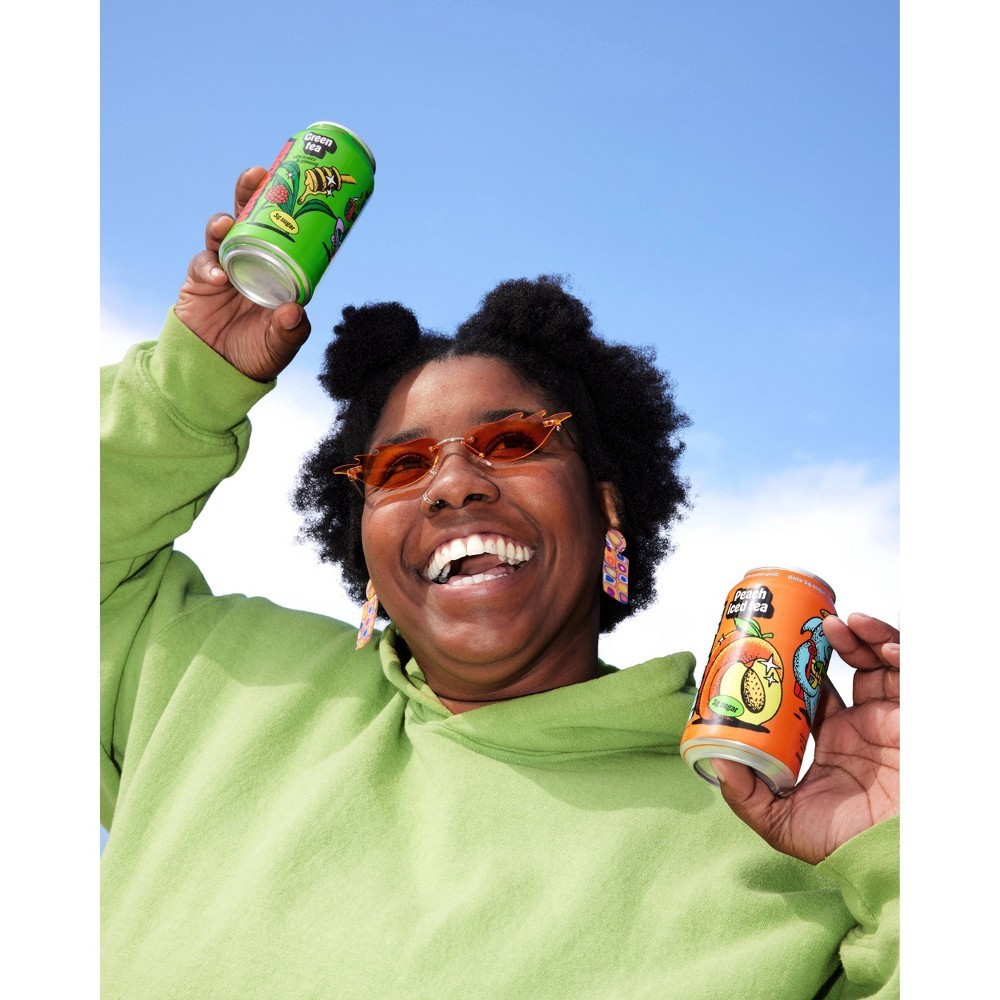 A woman holding up two Halfday Tonics iced tea cans and smiling