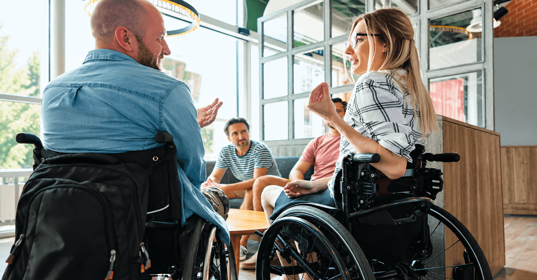 Wheelchair users and collaborators discussing ideas together in a bright shared workspace.