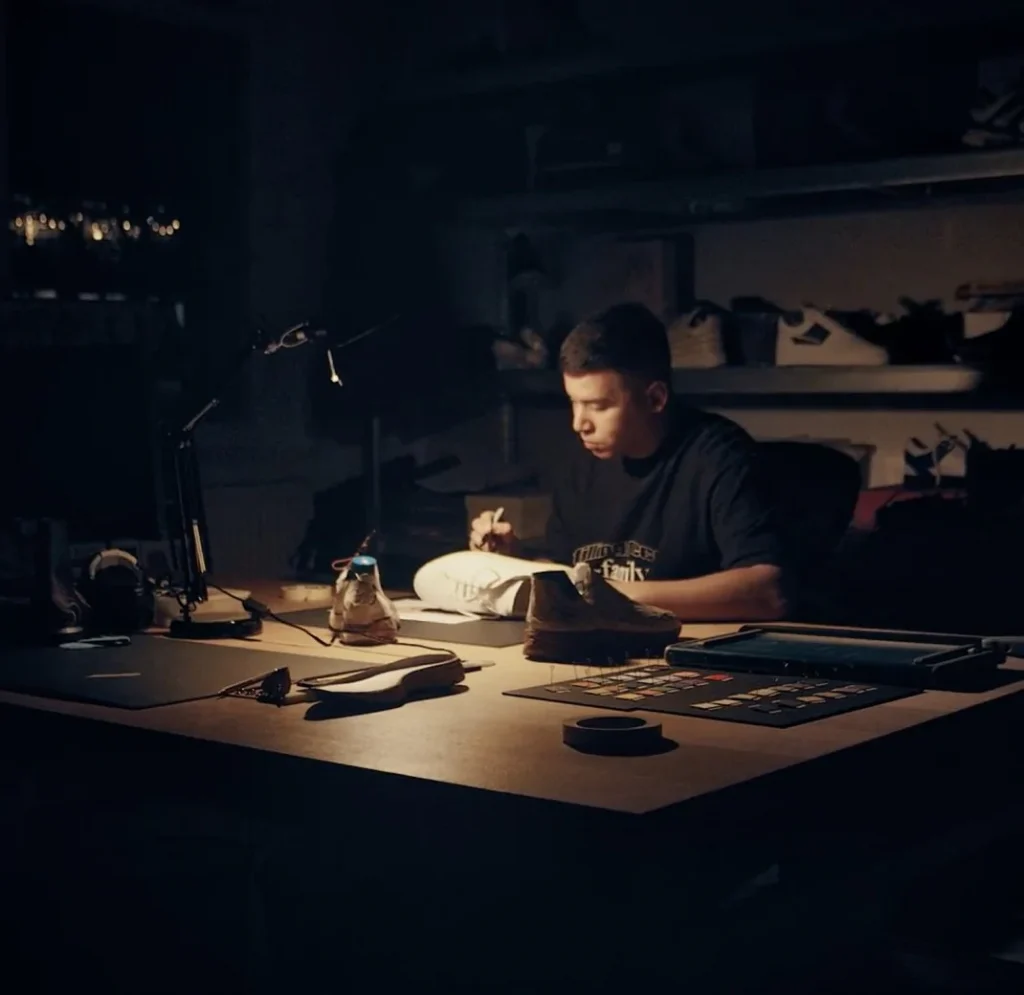 Designer working on a sneaker at a dimly lit desk, illustrating the Filling Pieces story