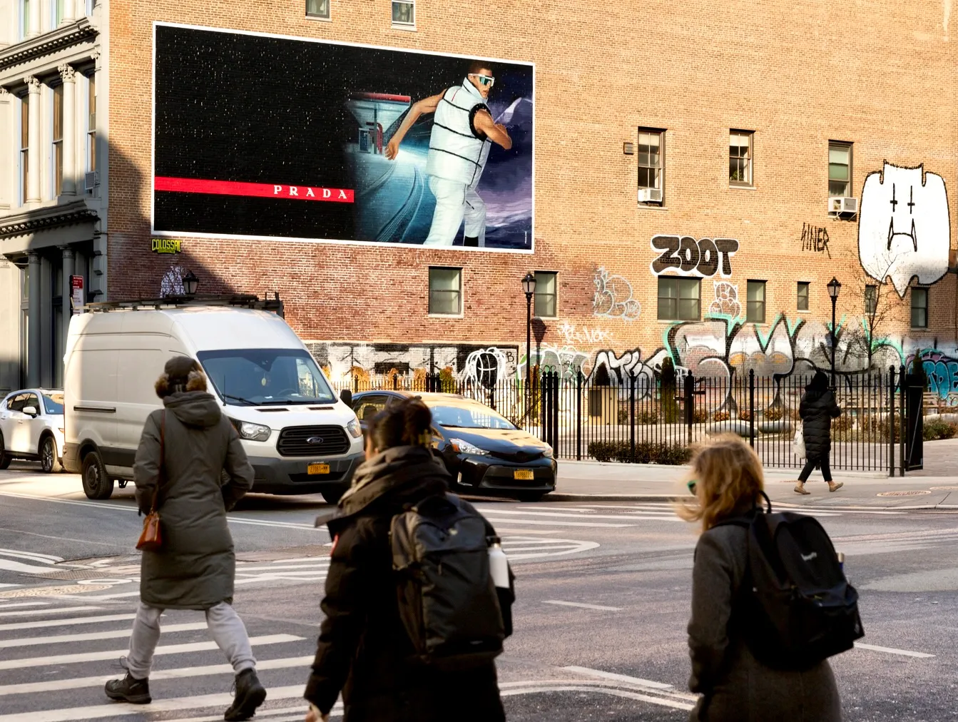 a man walking down a street past a large poster