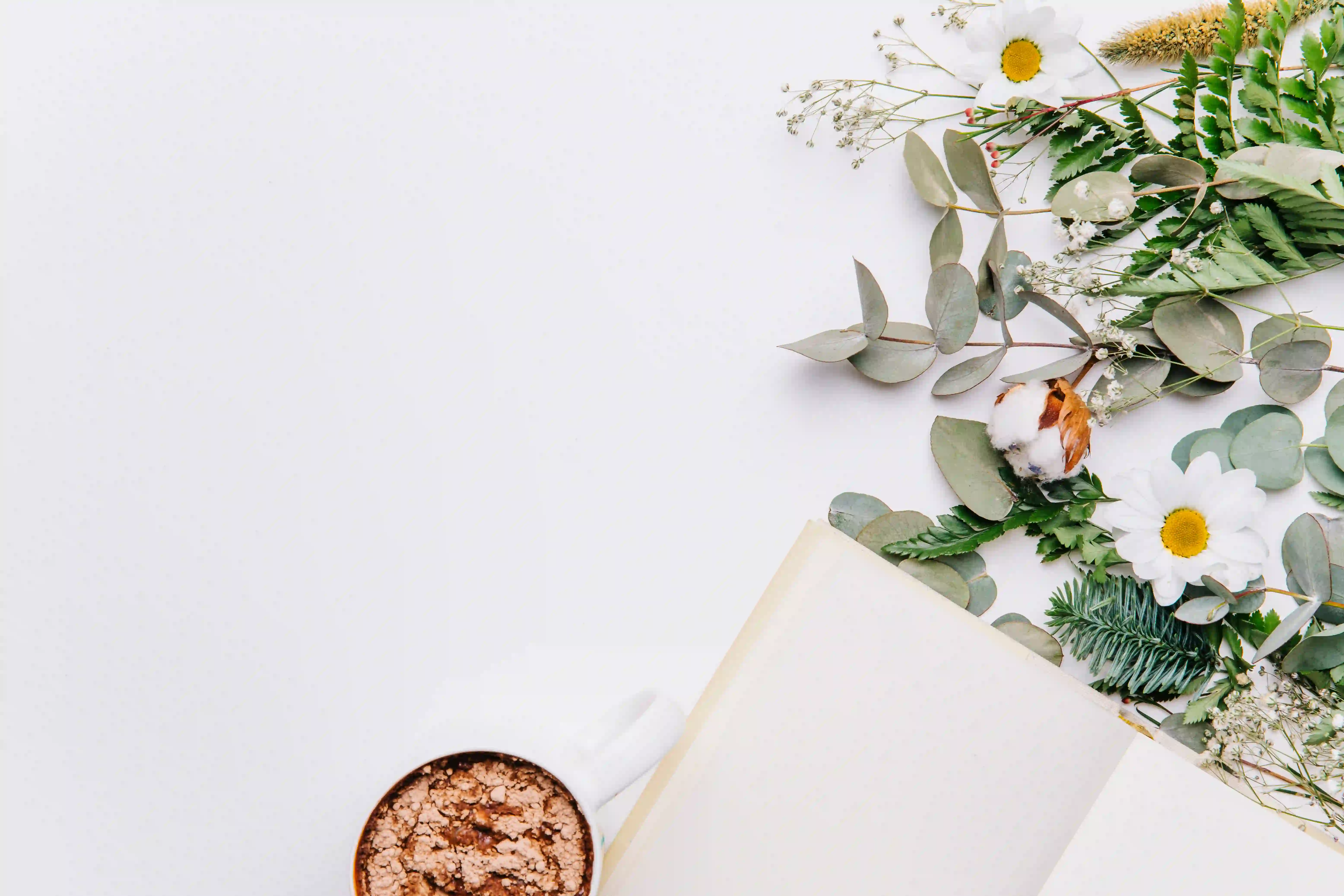 Carnet ouvert accompagné d'une tasse de café et de fleurs, créant une atmosphère douce et propice à l'écriture