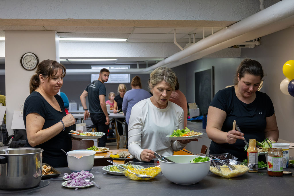 Membres de la communauté Progrès-Fit partageant un repas sain composé de légumes frais et protéines après l'entraînement.