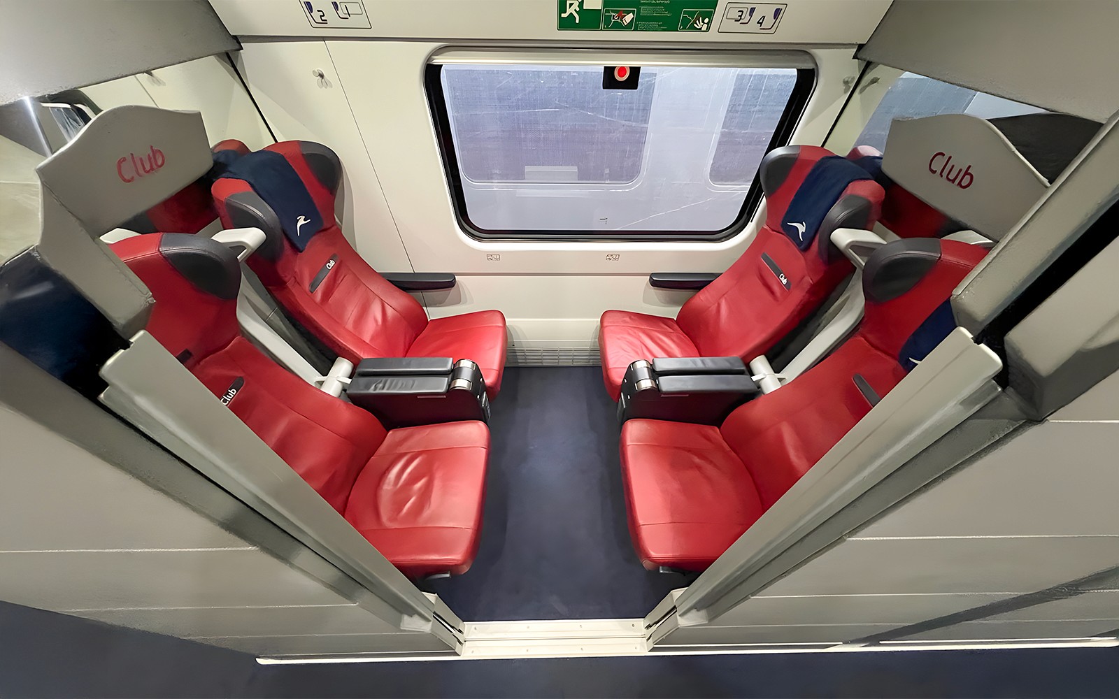 Italo train Club class seats with red upholstery and window view.