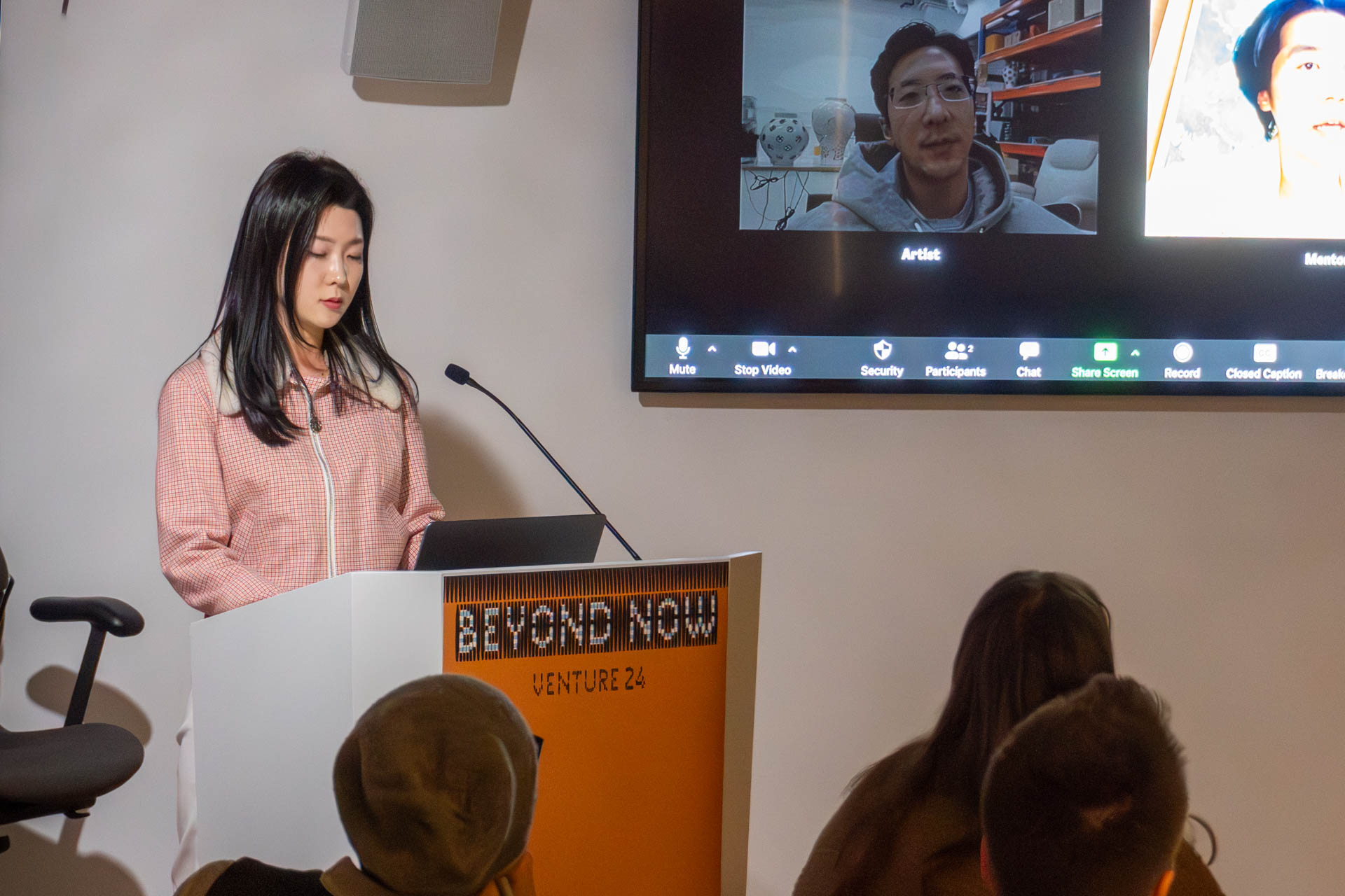 A lady at the podium giving a presentation to a class.