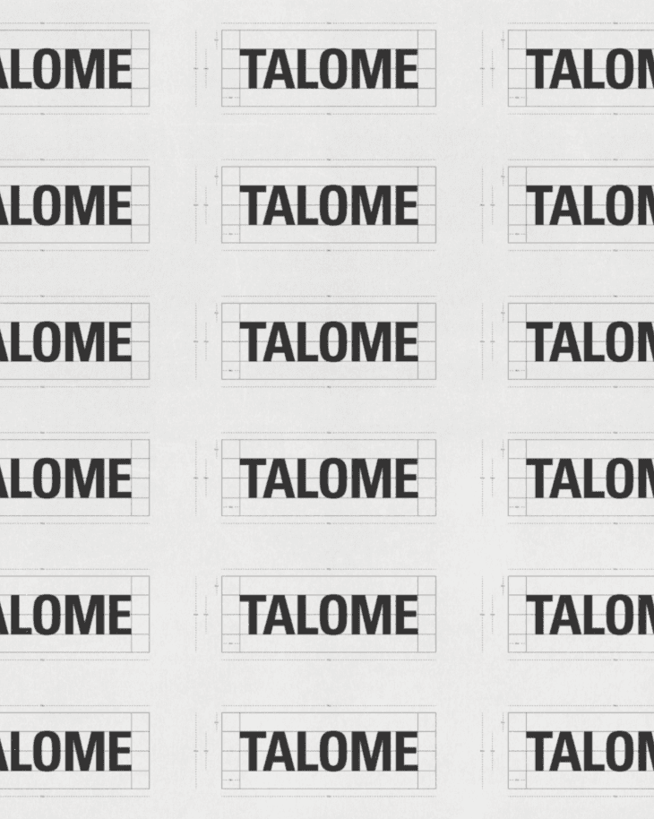 A smiling young man with crossed arms, wearing a plaid shirt and white t-shirt, poses against a dark background.