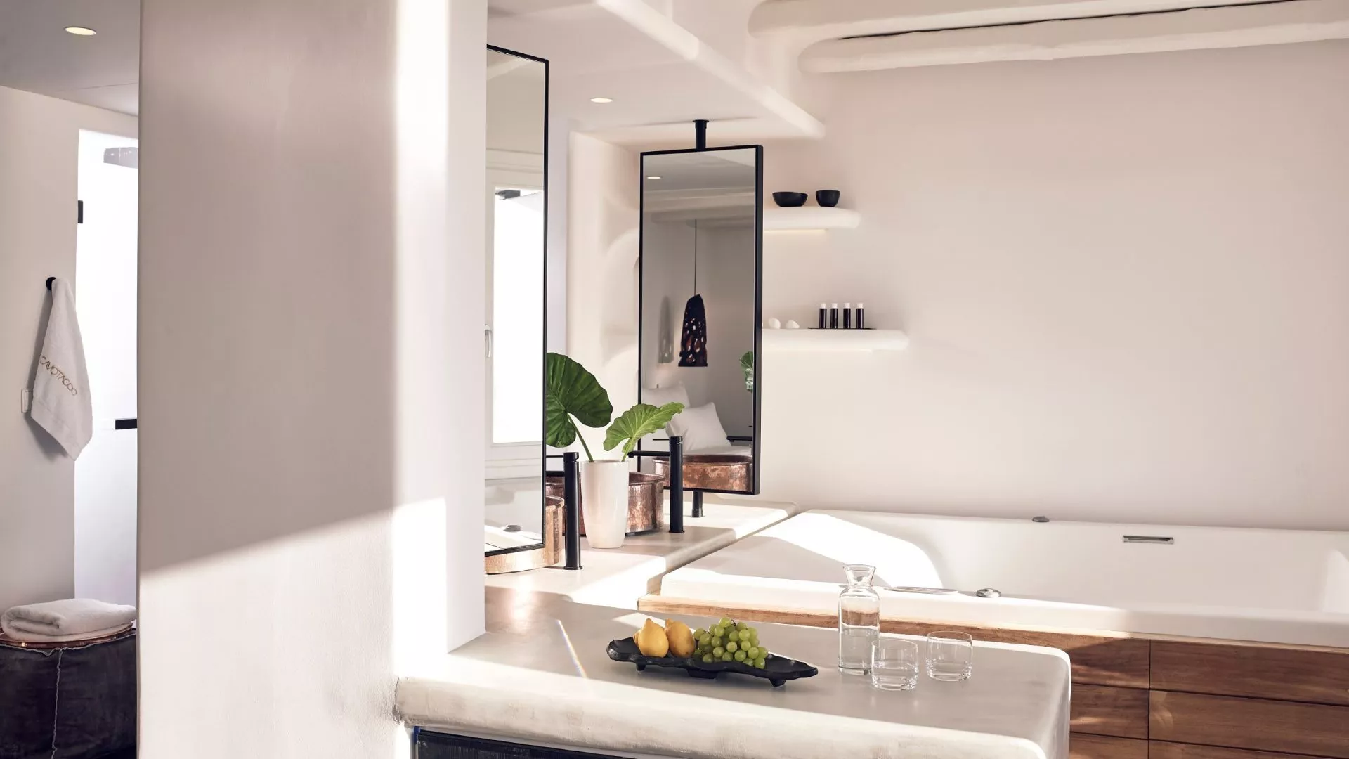 Luxuriöses Badezimmer mit freistehender Badewanne, Spiegeln und Obst