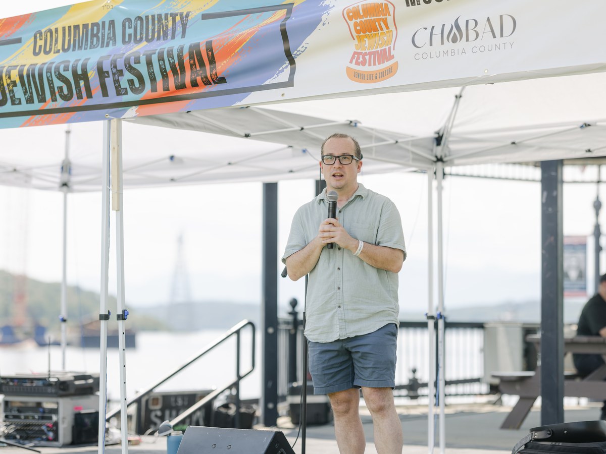 A speaker takes the microphone under the Columbia County Jewish Festival banner at Henry Hudson Riverfront Park. Photo: Tasha Hurley Photography