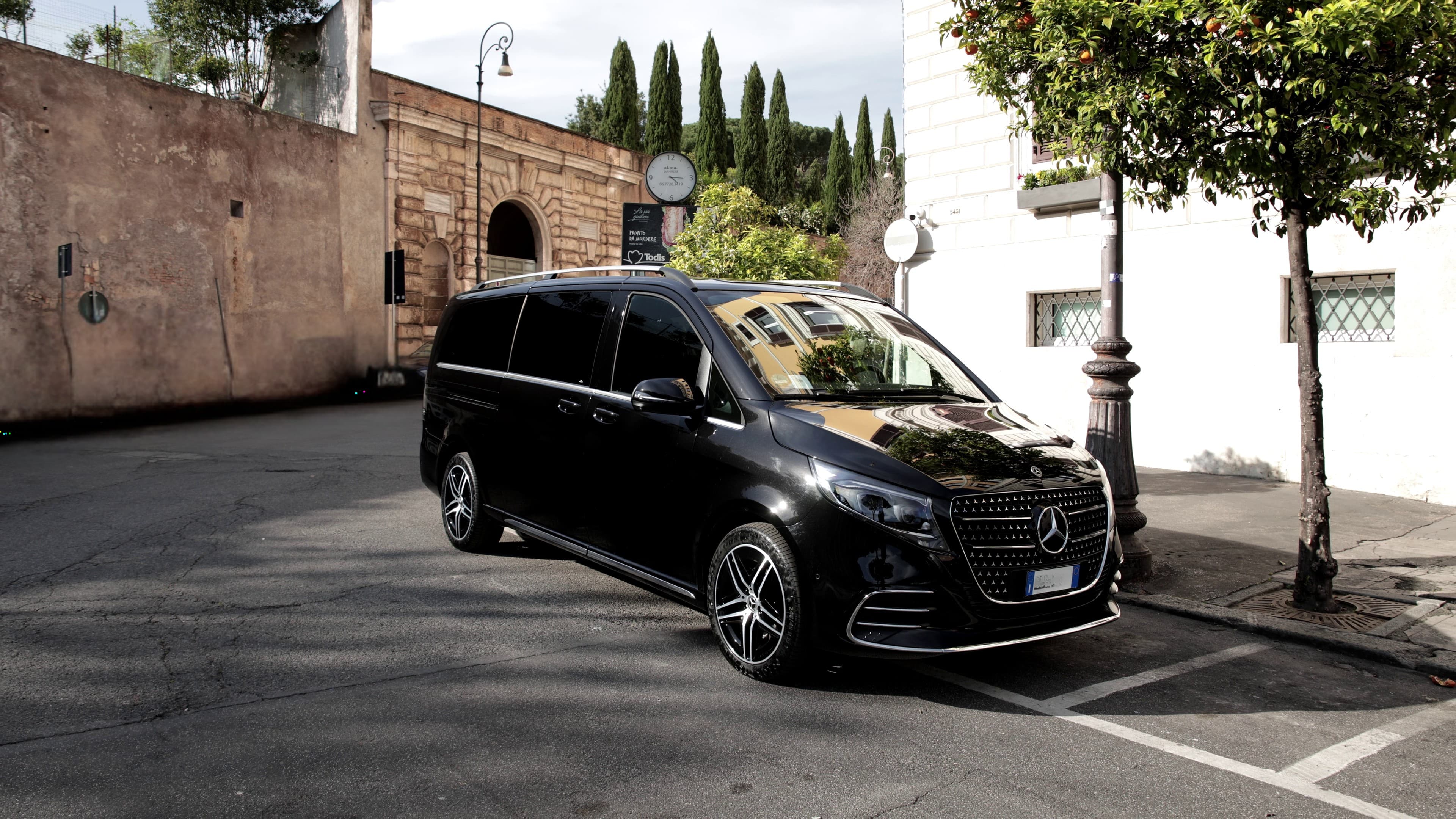 A Mercedes-Benz V-Class van along the sidewalk of a street in Italy.