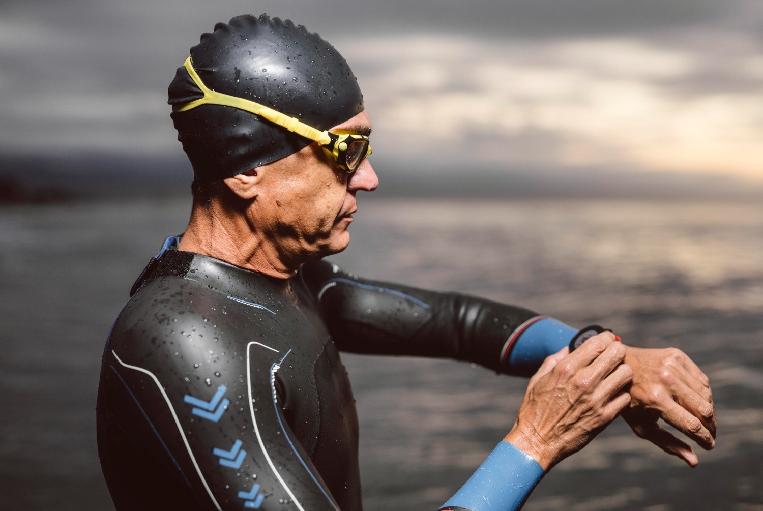 Triathlonista w piance przygotowujący się do startu w pełnym Ironmanie, sprawdzający zegarek przed wejściem do wody