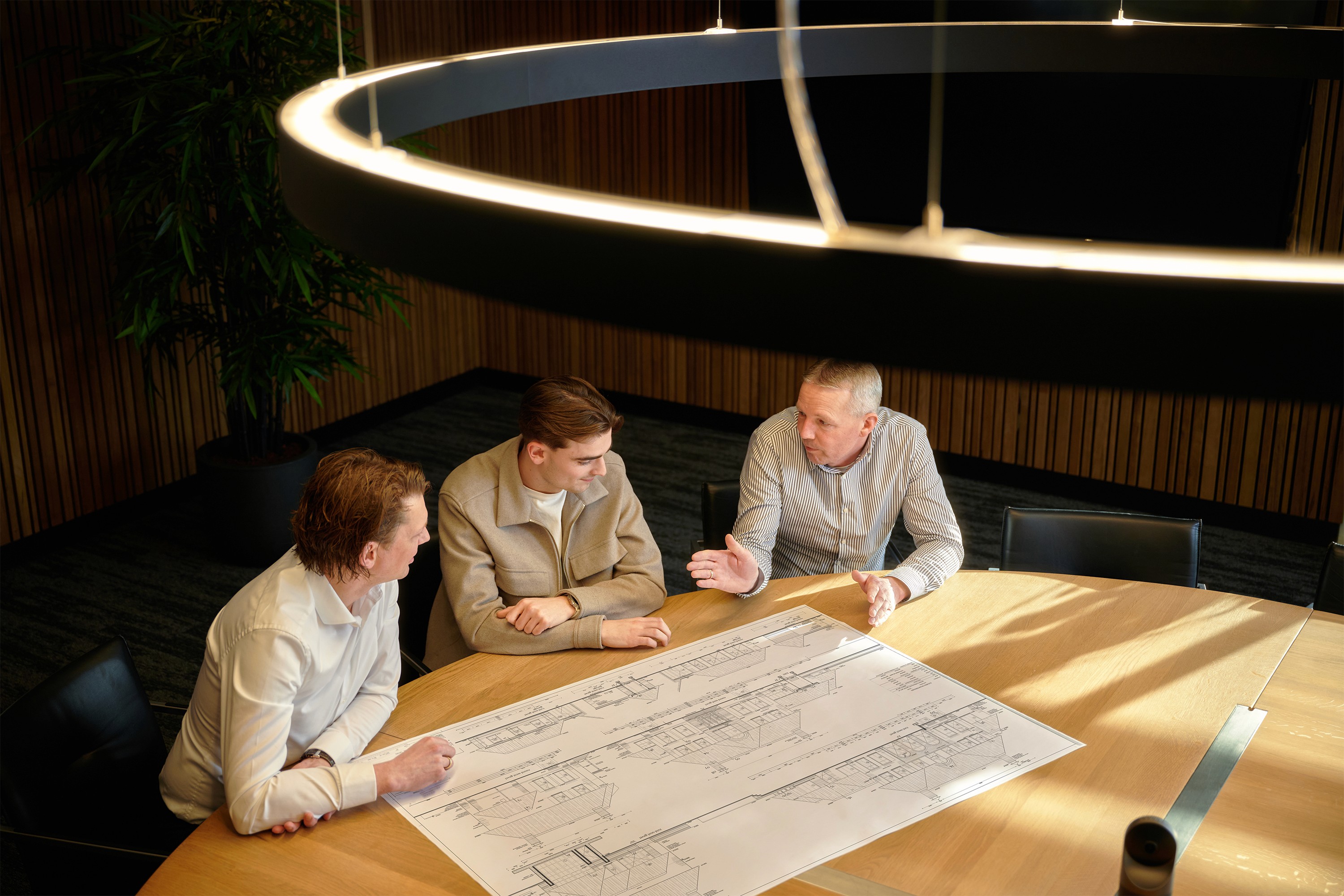 Collega's van Suyver/ TEAMWBC die bouwtekening bespreken aan tafel in sfeervolle vergaderruimte