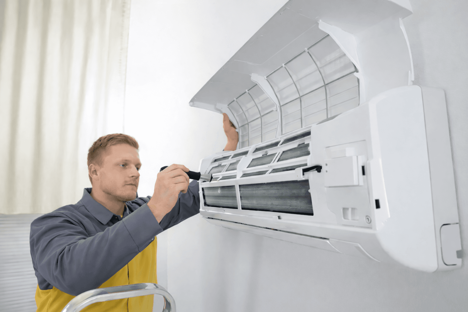 Technician removing air conditioner filter for routine care.