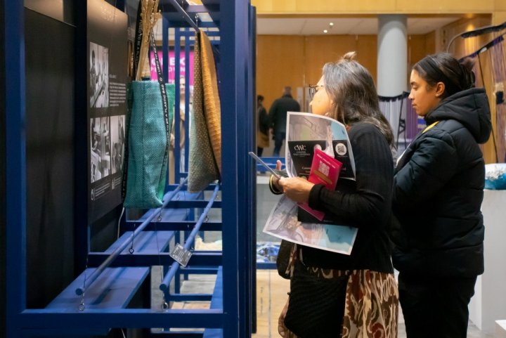 A rustic outdoor dining table set with wine glasses, cutlery, bread, and olives sits amidst lush vineyard rows, with a historic Tuscan villa in the background under a serene sky, capturing the essence of a picturesque Italian countryside landscape.