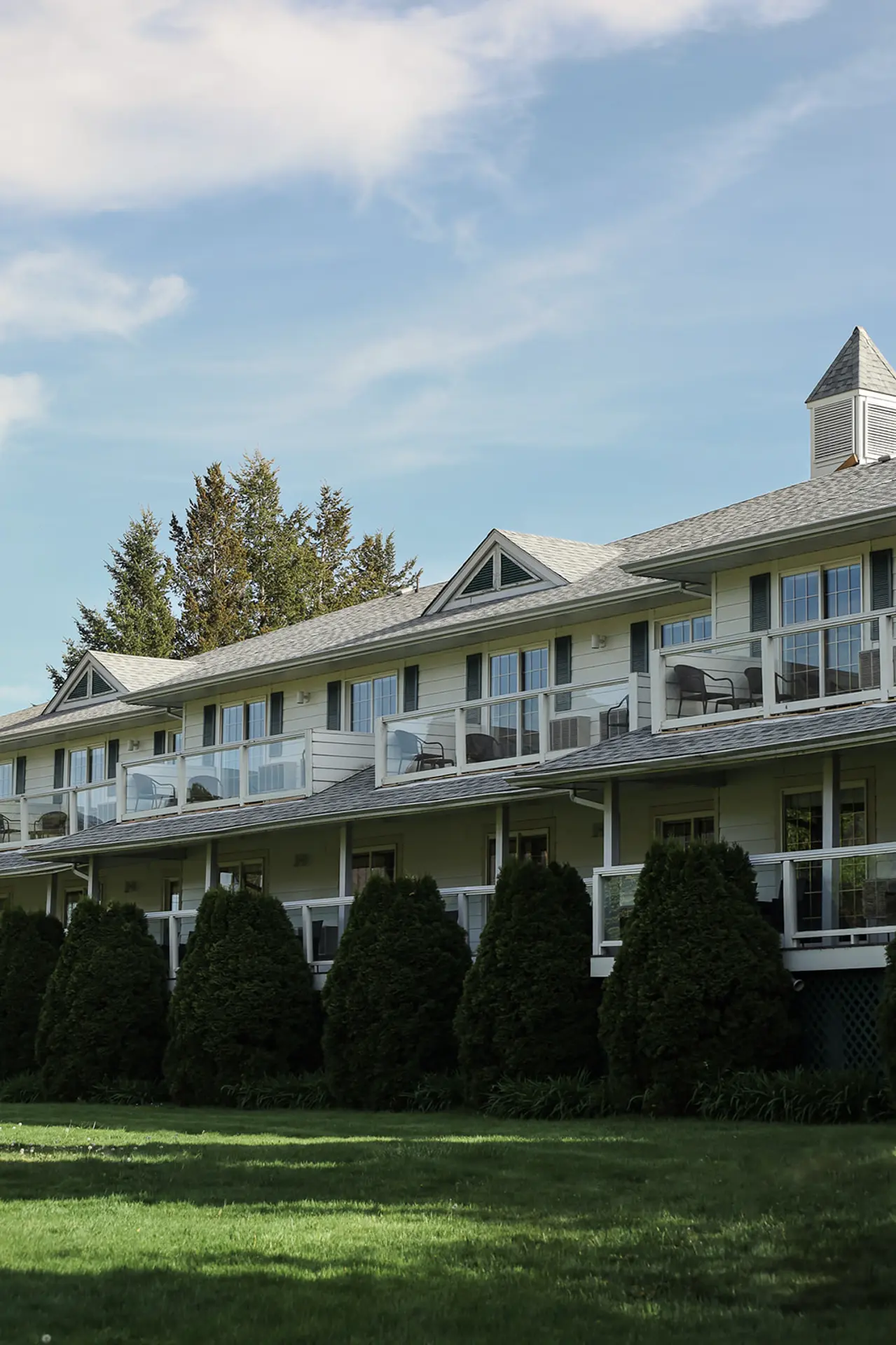 Exterior view of a multi-story building with balconies and a well-manicured lawn.