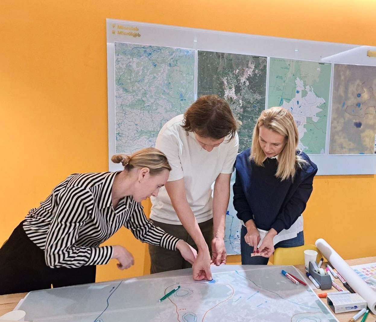 Three people collaborating over maps and documents during OPORA Foundation’s initiative to address water challenges in Klesiv, Ukraine.