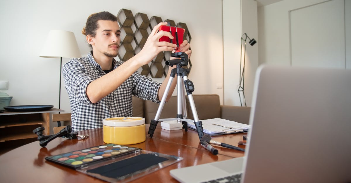 A male vlogger adjusts his camera on a tripod, preparing for a video shoot in a stylish home studio.