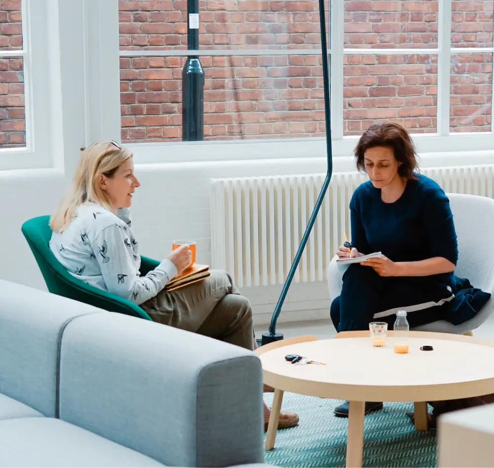 Photograph of two women in a casual office environment discussing their current project