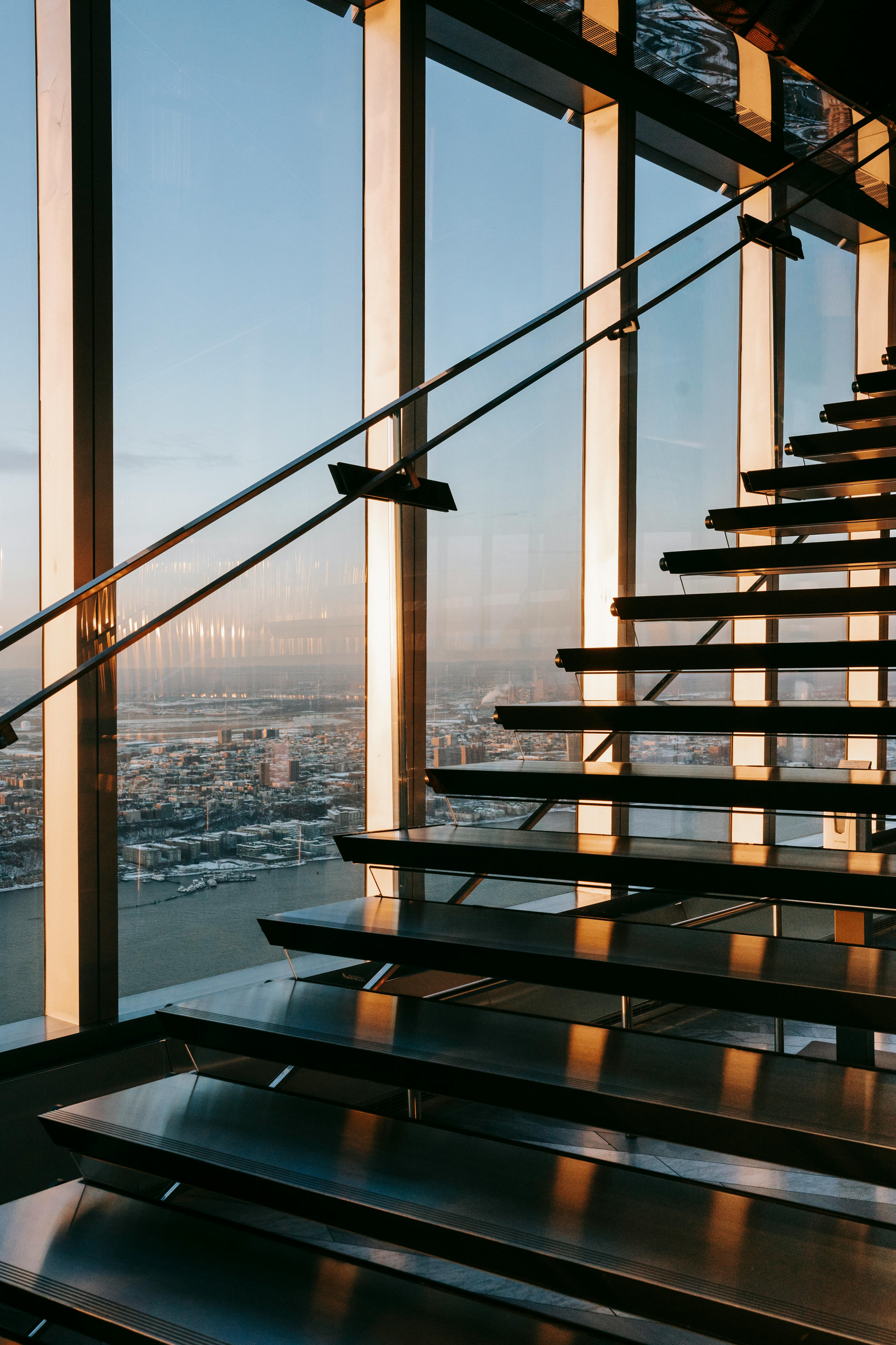 Modern office interior with glass walls, wooden accents, and a person walking up a staircase in motion blur.