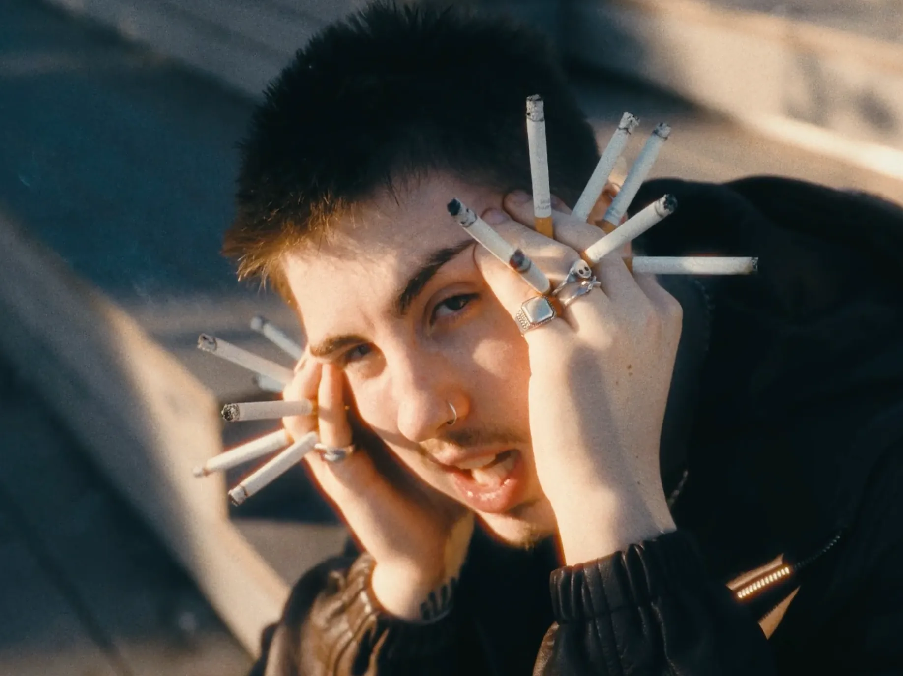 A man holding his head with cigarettes poking out of his fingers