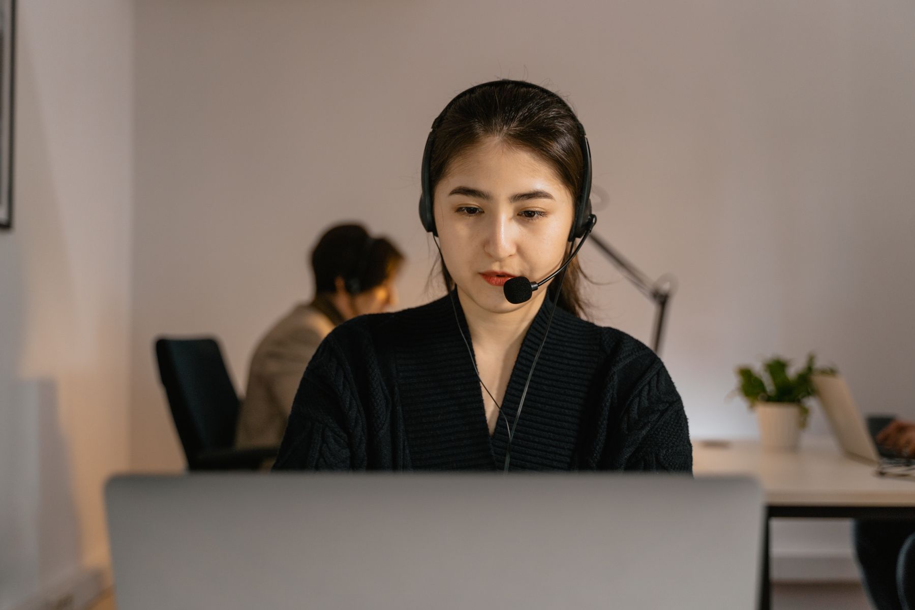 A contact-centre agent wearing a headset works at a computer.