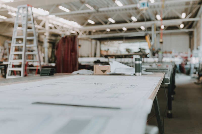 Blueprint on a table, with a ladder and other tools in the workshop.