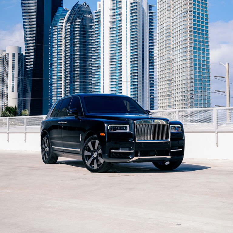 Front 3/4 view of a black Rolls-Royce Cullinan parked in front of a city skyline.