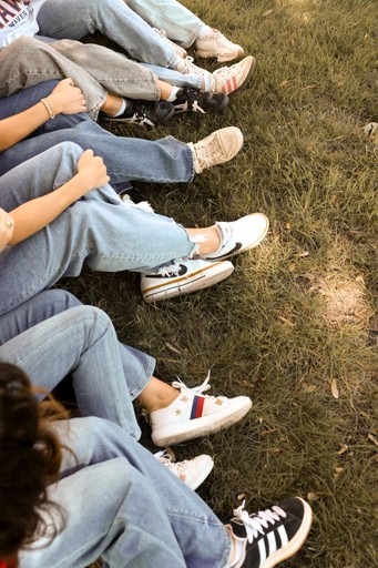 Eine Gruppe von Teenys sitzt entspannt nebeneinander im Gras