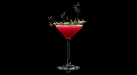 A closeup of a Pomegranate Bliss Martini drink against a dark background.