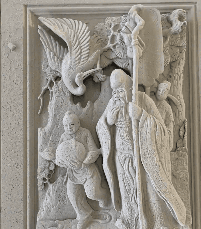 A traditional stone relief sculpture featuring a crane and Chinese figures, showing elegant and lifelike carvings.