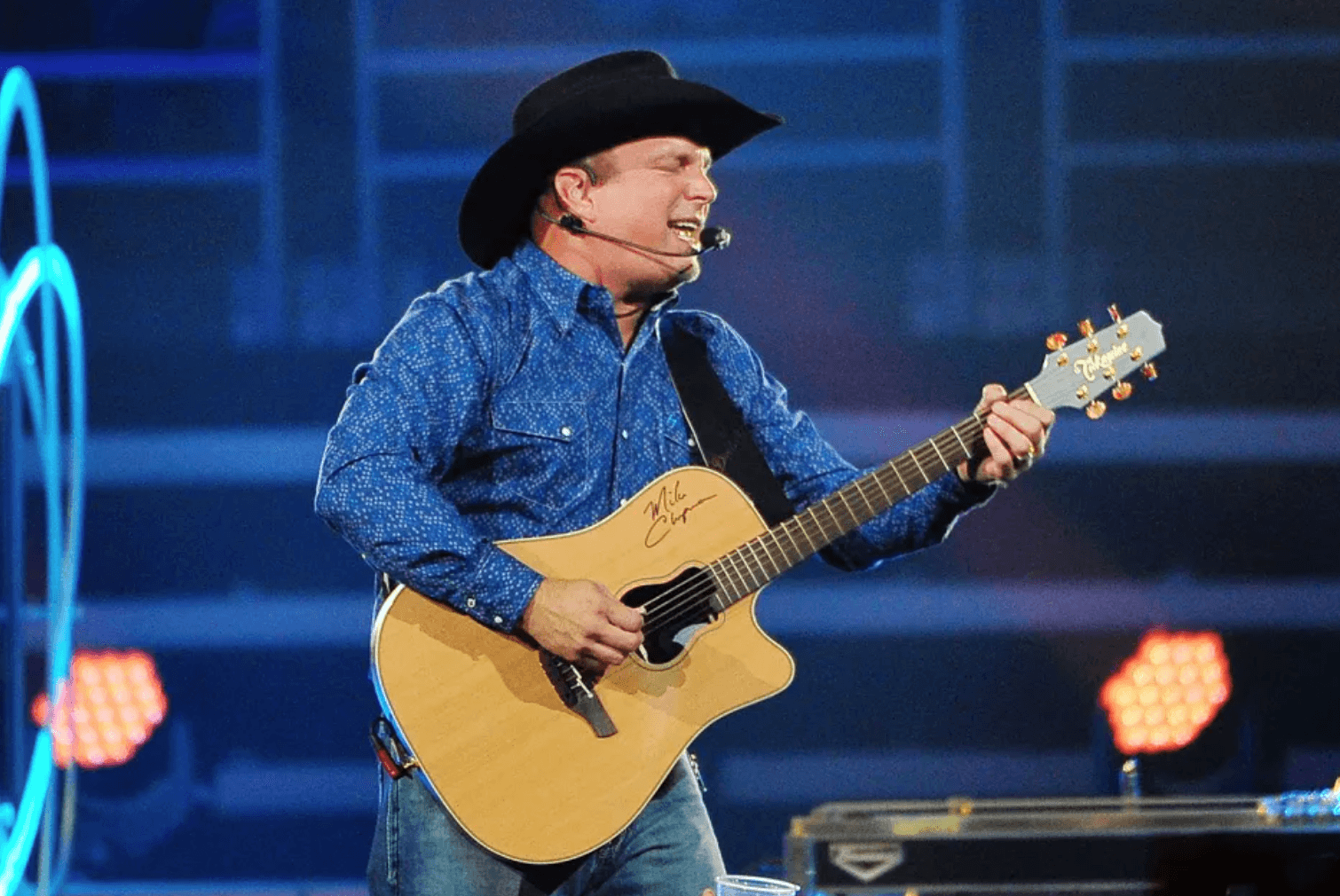 Country artist Garth Brooks performing on stage with a mic and guitar