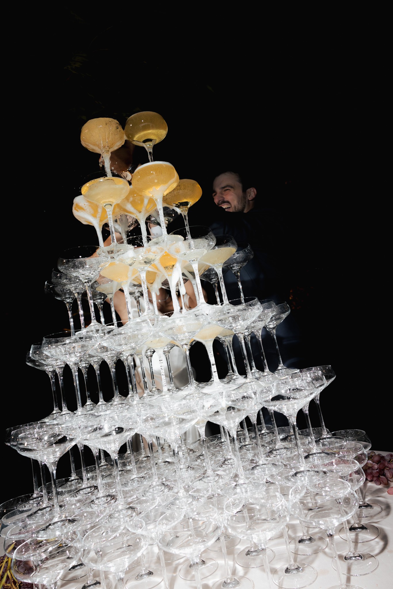 Piramide di champagne con flute e sposi sullo sfondo al ricevimento di matrimonio al Castello di Scipione