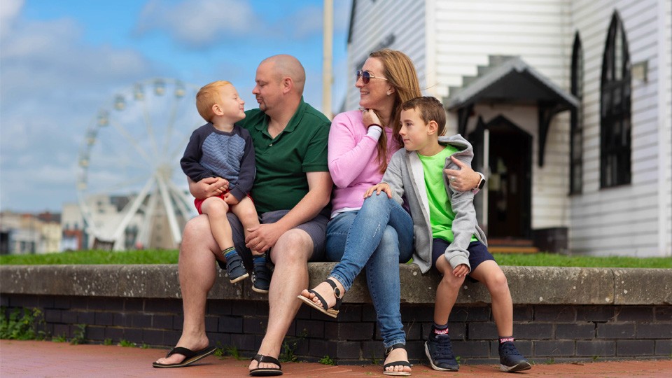 A family sitting on a low wall outside the Norwegian church