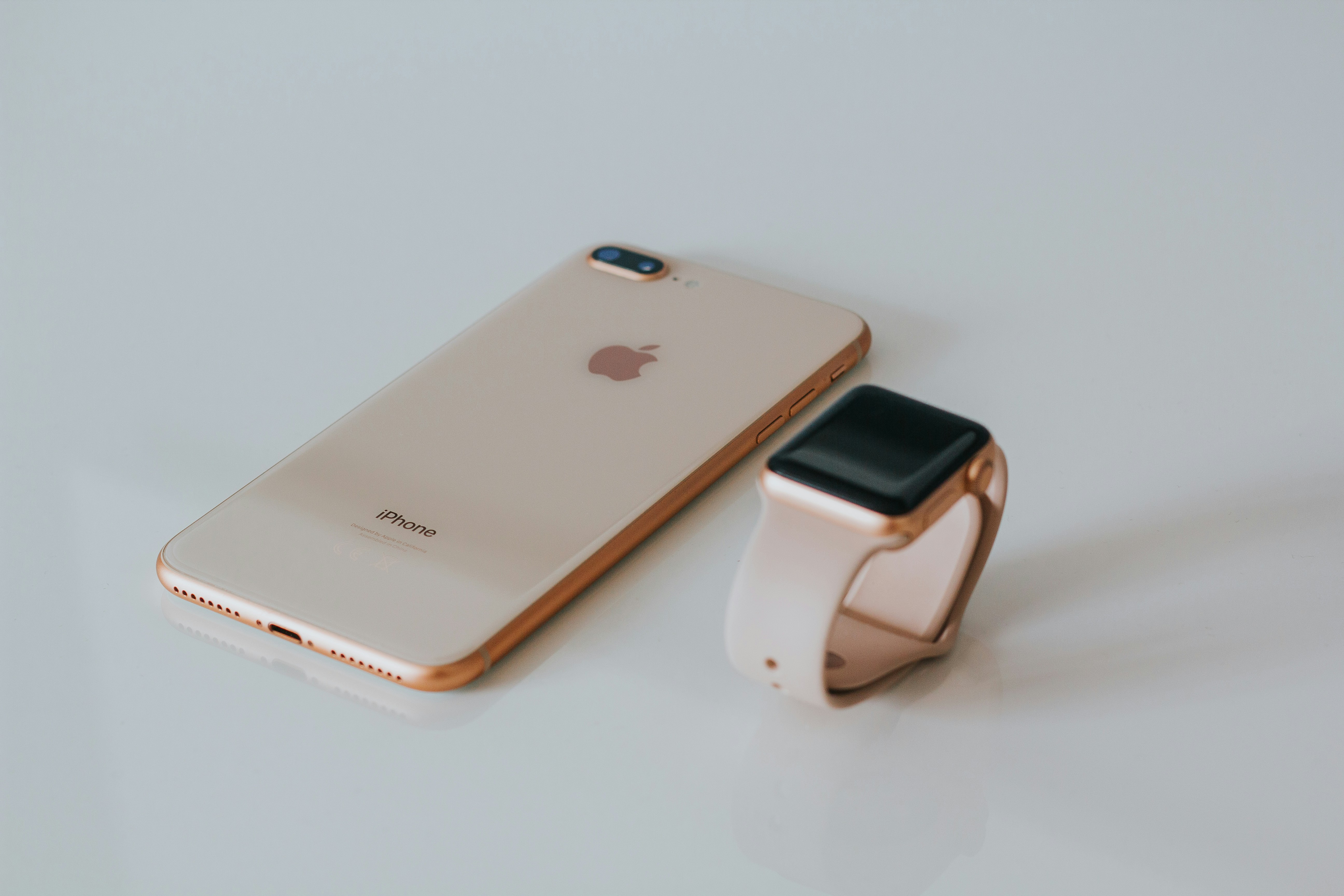 Gold iPhone and rose-gold Apple Watch styled together as an elegant flat-lay
