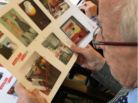 Oudere man bekijkt samen oude foto's en dia's uit de jaren 60