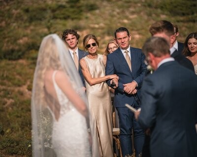Wedding guests watch the ceremony from behind the veiled bride.