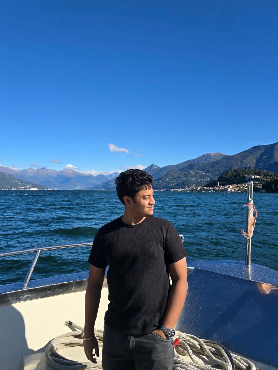 A young man with glasses and a denim shirt sits confidently against a blue wall. Art and cacti decorate the space, conveying a creative vibe.