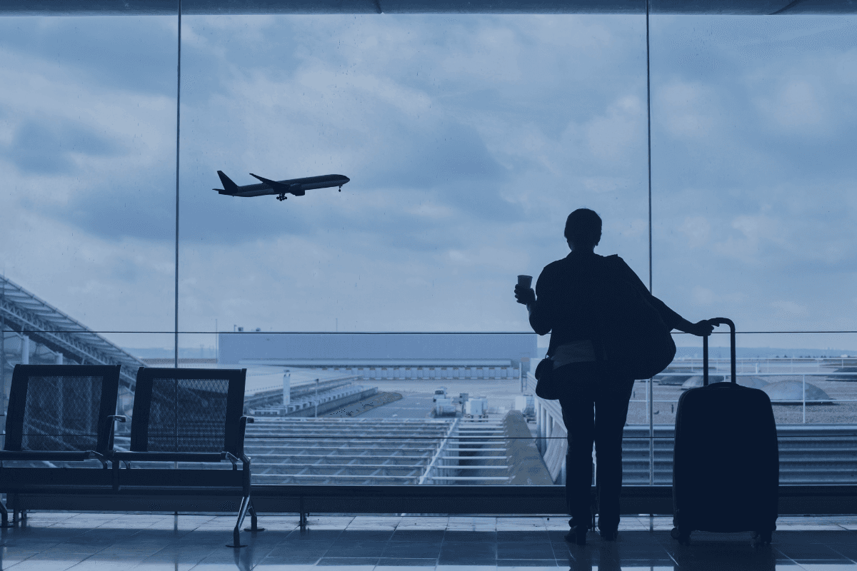 Professional individual with luggage overlooking runway, representing the benefits of a second passport