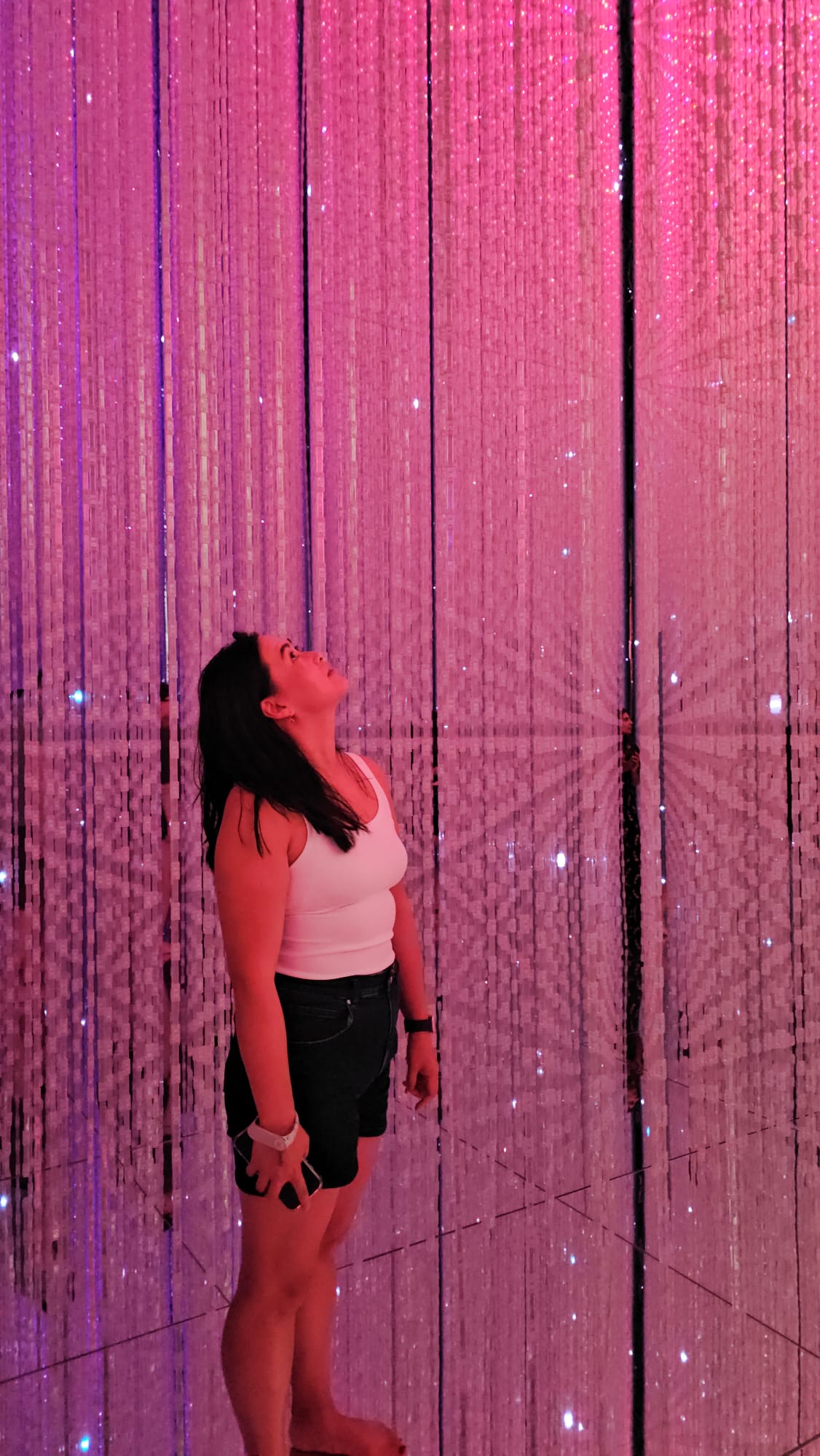 Ann Luong in Teamlab Tokyo looking at the light installation that's glowing pink