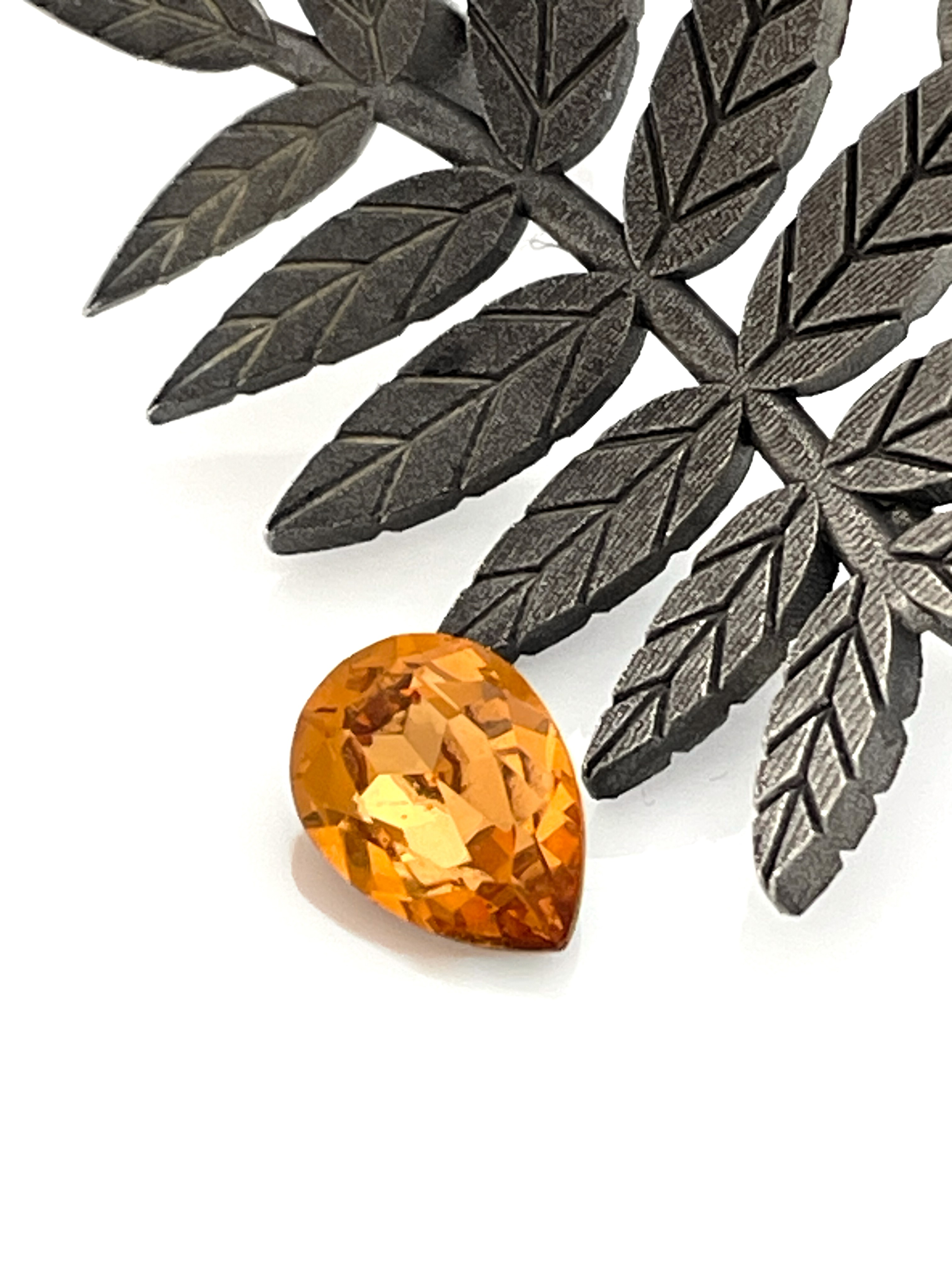 Leaf pendant with a cast surface and a gold-colored crystal.