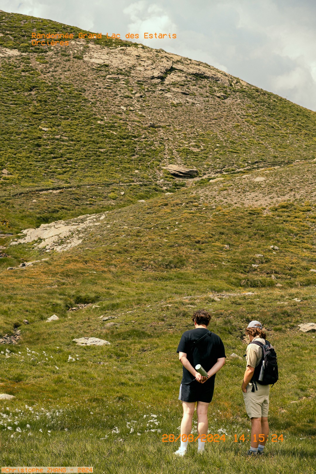 Deux randonneurs admirant les vastes prairies alpines sur le sentier vers le Grand Lac des Estaris
