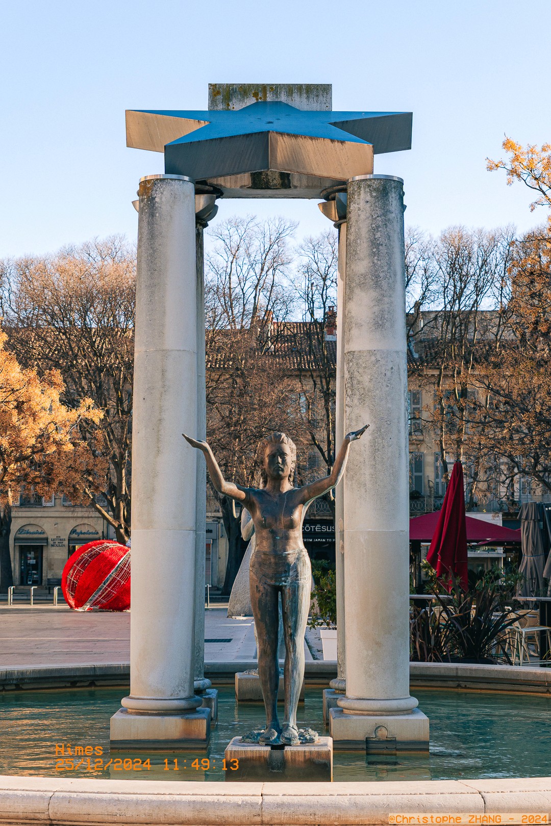 Fontaine artistique avec statue féminine sous une structure étoile.