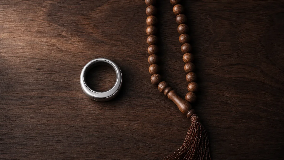 Silver smart tasbih ring beside traditional wooden misbaha beads on a walnut table