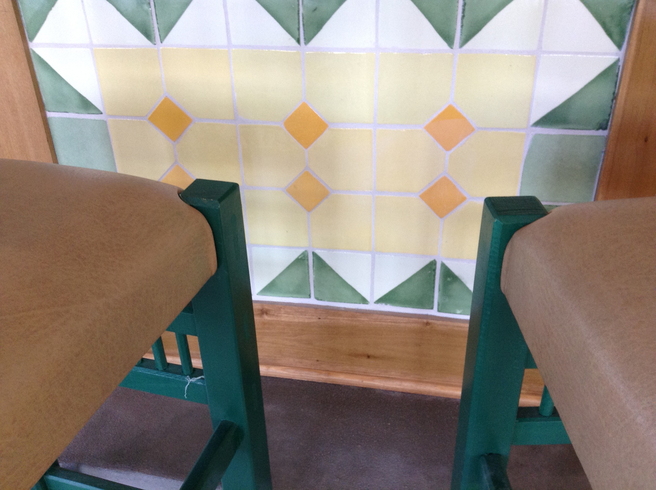 a tile pattern on a wall with the corners of two high-stools for a bar in the foreground