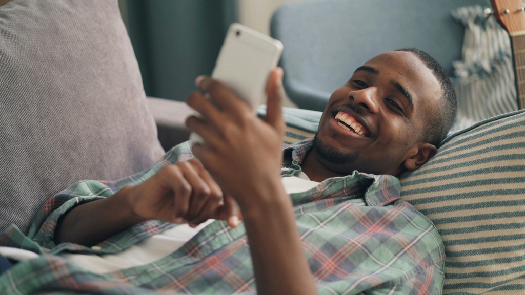 Smiling Man Lying Down with Smartphone