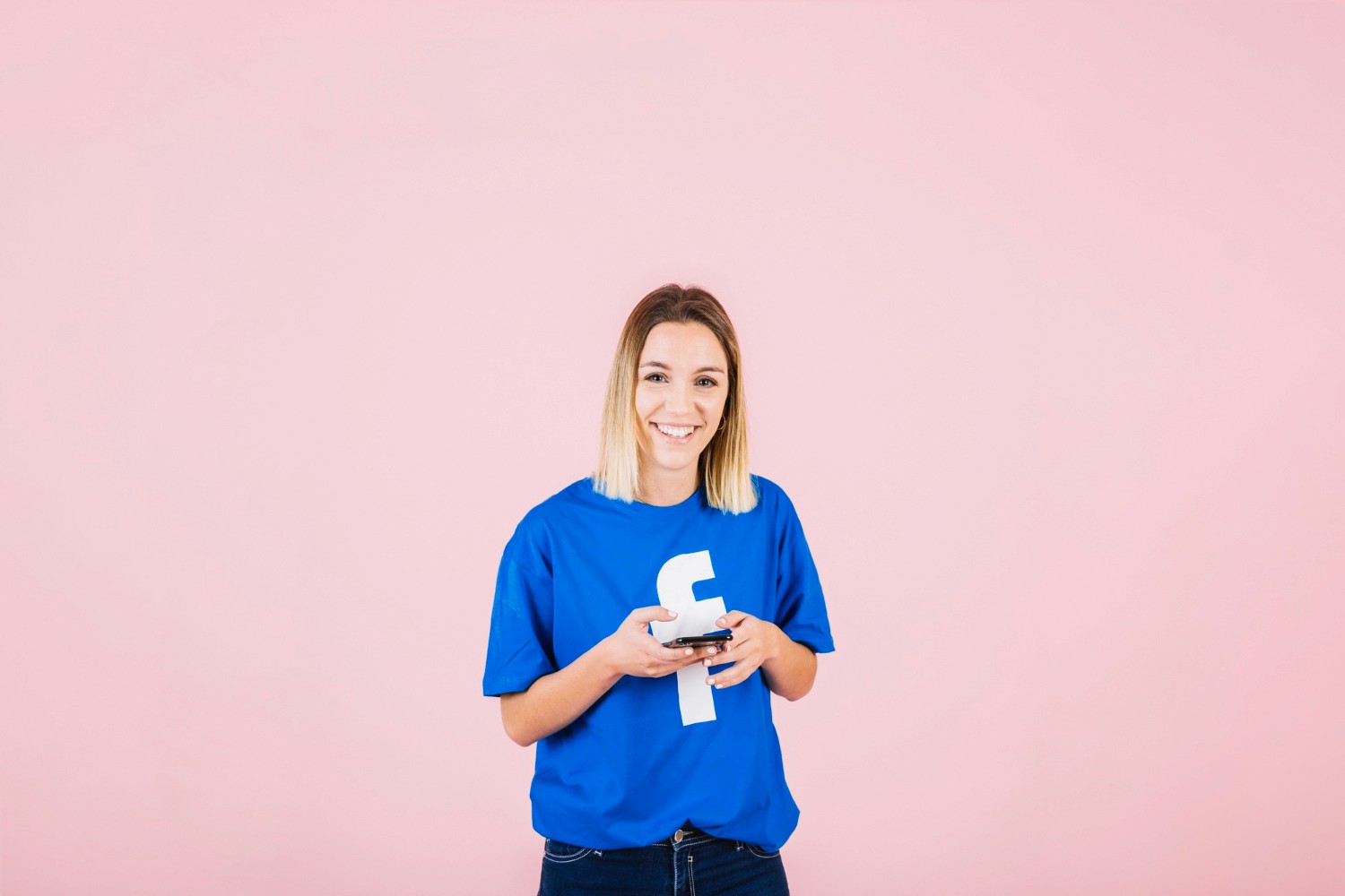  A woman in a blue shirt is holding a phone, looking focused and attentive to her device.