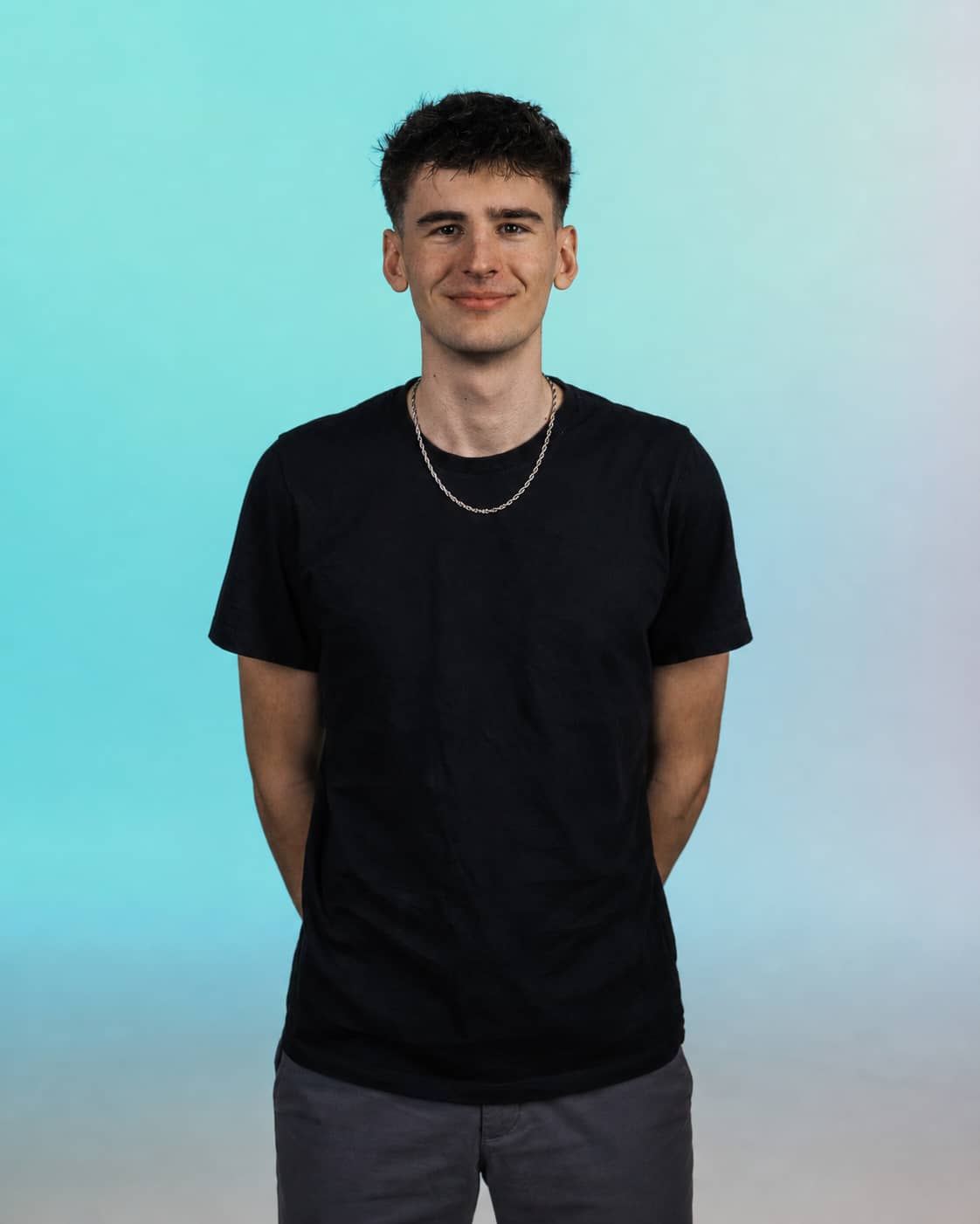 Vincent Gollon, Mediendesigner im Reelzz Team, vor hellblauem Hintergrund. Das Bild zeigt ein Teammitglied der Social Media Agentur Reelzz für professionelle Content Produktion und visuelle Gestaltung.