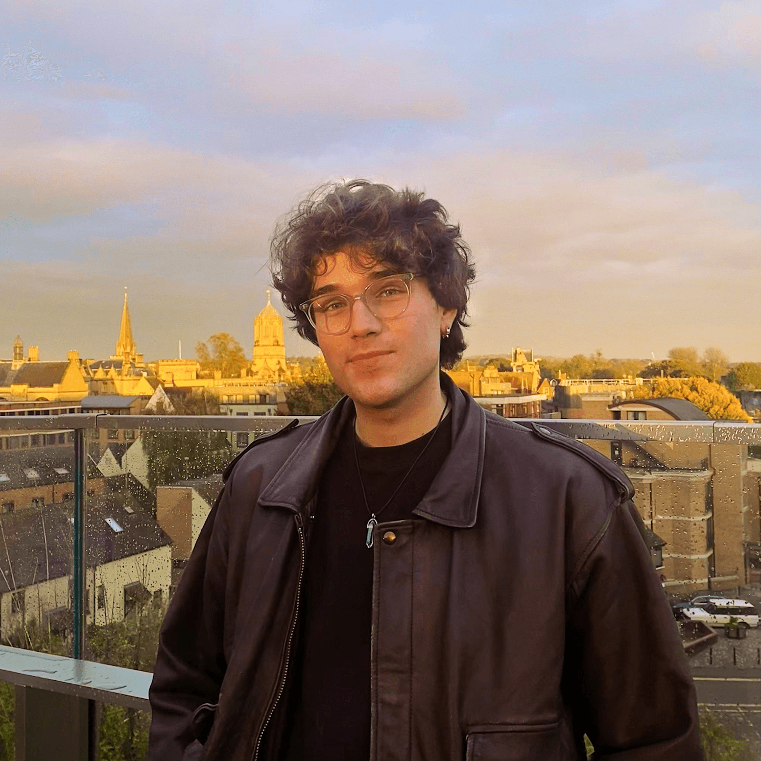 Person wearing a blue puffer jacket and red backpack standing in front of a light blue building on a city street.